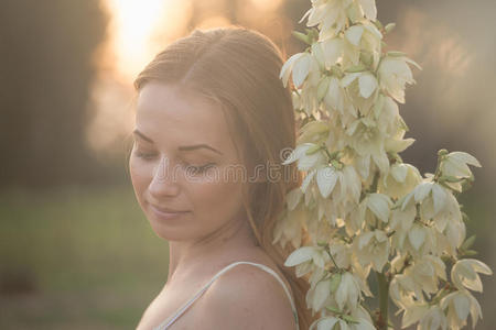 特写肖像.年轻漂亮的漂亮女人穿着长裙，在田野上戴着白花