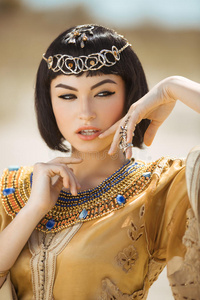 美丽的女人，时尚的化妆和发型，如埃及女王克利奥帕特拉户外对抗沙漠