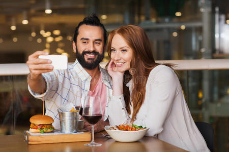 一对夫妇在餐厅用智能手机自拍