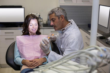牙医向女性病人展示口腔模型