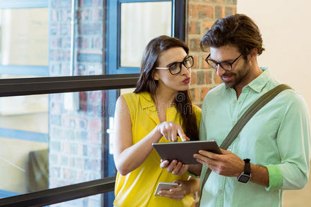 同事互动企业高管和同事在使用数字平板电脑时进行互动照片