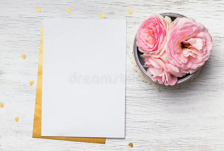 白纸和可爱的粉红色花在白色的木桌上照片