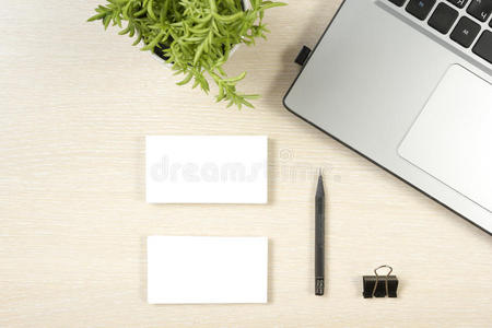 名片空白，笔记本电脑，花和铅笔在办公桌桌面视图。 企业文具品牌模型