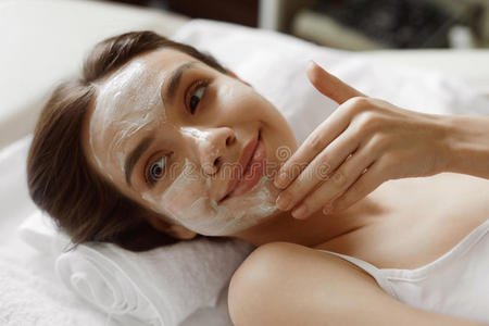 面部皮肤护理。 美丽的女人带着美容面膜在水疗中心