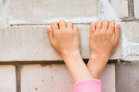 顶部击剑交叉的孩子们双手抓住砖墙照片