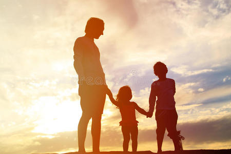 父亲带着儿子和女儿在日落海滩散步