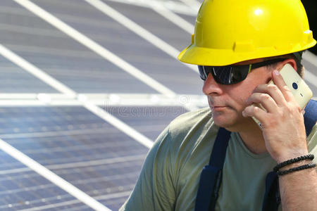 绿色能源，太阳能电池板和带手机的工人