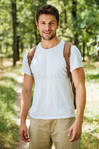 兴高采烈的年轻人背着背包站在森林里