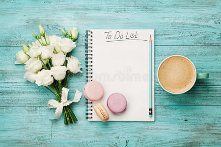 咖啡杯与通心粉，白花和笔记本与做清单上的蓝色乡村桌子从上面。 漂亮的早餐。 平躺