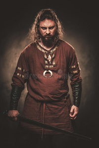 维京服装愤怒的维京与剑在传统的战士服装,摆在一个黑暗的背景.照片