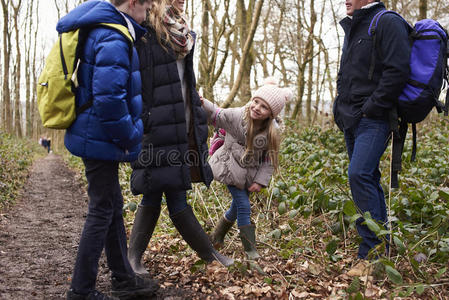 家庭站在一片树林里，他们的年轻女孩在玩耍，作物射击