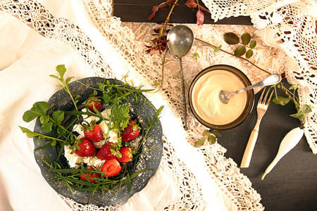 旧白色花边桌布上有草莓的黑色盘子。