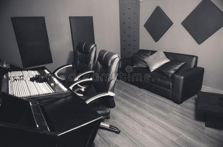 一流的专业录音室，配有调音台和两把椅子的大桌子，声乐室的窗户，沙发
