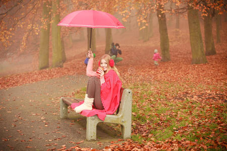 带着雨伞坐在公园里的女孩