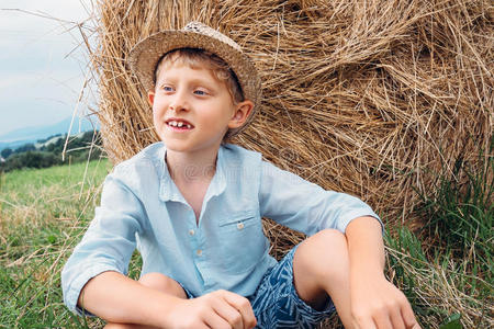 男孩坐在田里的大干草堆附近