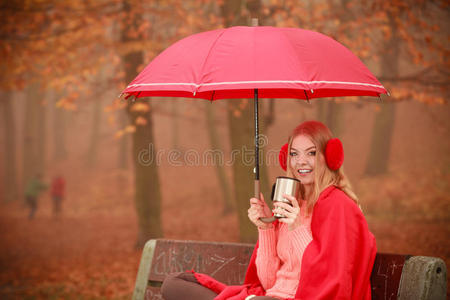 带着雨伞坐在公园里的女孩