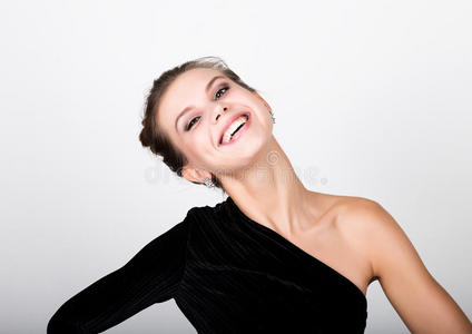特写时尚照片的年轻女士穿着优雅的黑色连衣裙，嬉戏的女人微笑