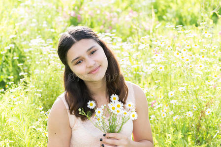 少女带着一束雏菊在夏天的草地上