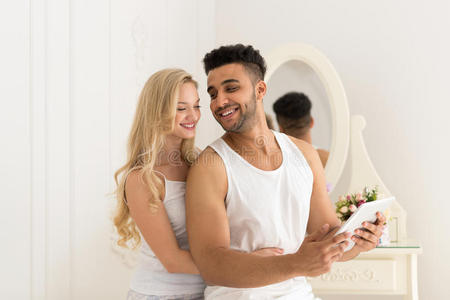 美丽的夫妇拥抱使用平板电脑快乐的微笑,年轻的西班牙裔男女相爱照片