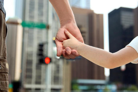 父亲牵着女儿孩子的手在红绿灯后面照片
