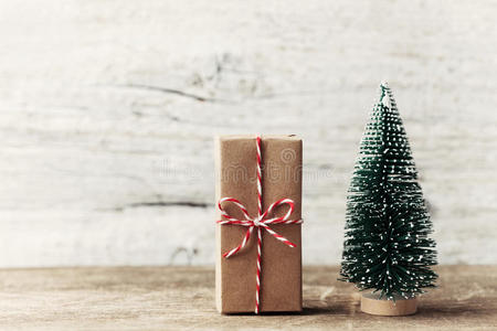 礼品盒包装在牛皮纸和小装饰杉树在木制乡村背景。 圣诞节和新年概念。