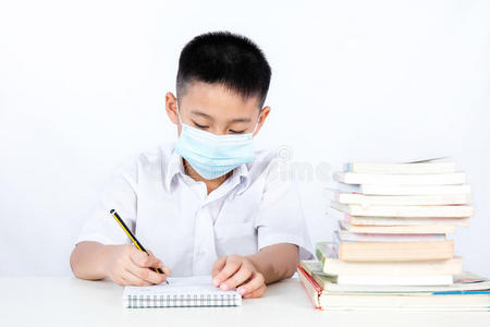 亚洲中国学生男孩戴着保护面具写作