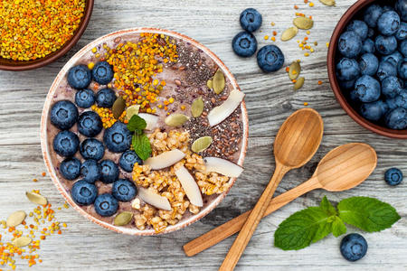 阿卡伊早餐超级食品冰沙碗，上面有辣椒亚麻和南瓜籽蜜蜂花粉麦片椰子和蓝莓