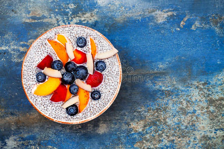 排毒和健康超级食品早餐碗的概念。 纯素椰奶奇亚种子布丁在乡村餐桌上与各种水果