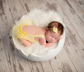 有趣的睡觉婴儿穿着黄色连衣裙在圆床上