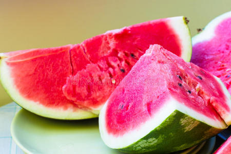 果肉果汁一片多汁的成熟西瓜,在浅绿色的盘子上有肉质的粉红色果肉.