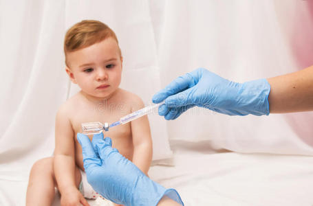医生拿着注射器给生病的婴儿注射疫苗