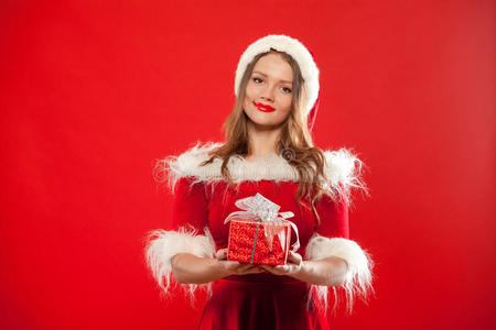 圣诞节，圣诞节，冬天，幸福的概念微笑的女人戴着圣诞老人的帽子，带着礼品盒，红色背景