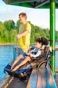 父亲在码头上钓鱼，残疾的儿子坐在轮椅上