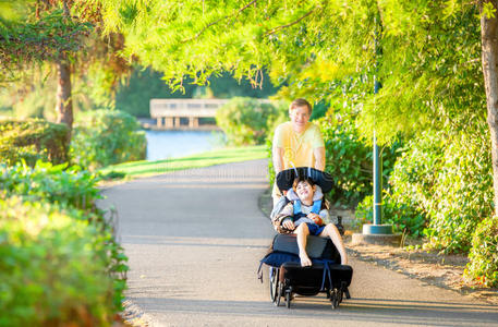 父亲和残疾儿子在公园坐轮椅走路