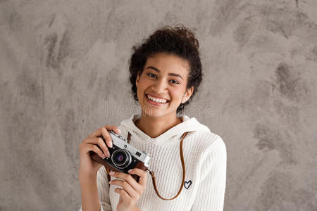 非洲女照片微笑着，拿着相机在米色背景上。