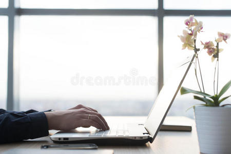 双手在笔记本电脑键盘上打字。 一个人在他的工作场所的办公室工作