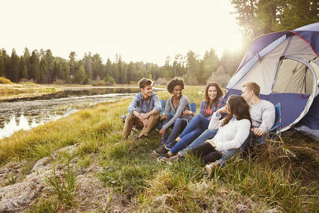 朋友们在露营旅行中，在湖边的帐篷旁放松