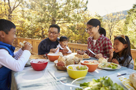 亚洲家庭在森林的甲板上的桌子上吃饭