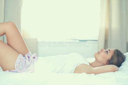 美丽的年轻女人躺在床上舒适而幸福