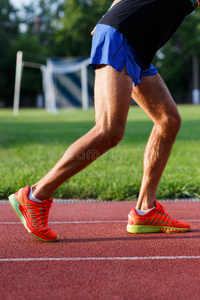 运动肌肉男的腿在户外跑步轨道上运动