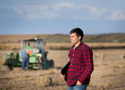 农民在田间与拖拉机在背景