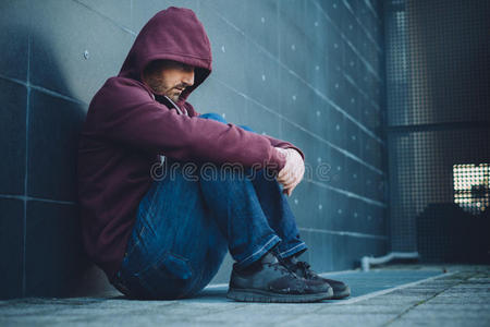 一个年轻人坐在屋顶上的画像.在夕阳的背景下.孤独的概念路.