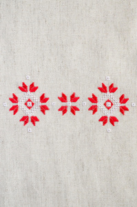 红色和白色棉线在亚麻上的元素手工刺绣。 刺绣背景。