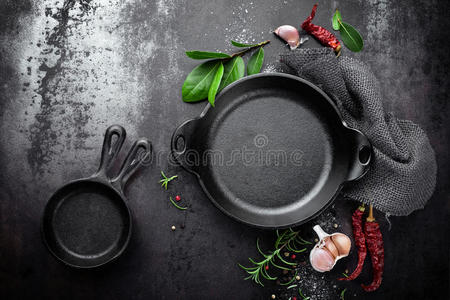黑色金属烹饪背景上的铸铁锅和香料