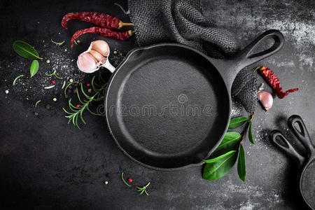 黑色金属烹饪背景上的铸铁锅和香料