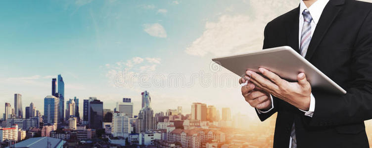商人在数字平板电脑户外工作，城市全景背景