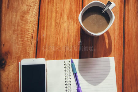 一杯咖啡，智能手机和笔放在笔记本上