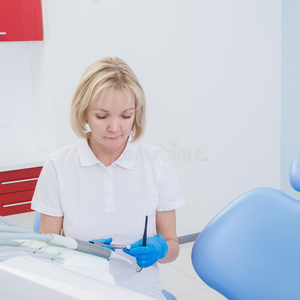 牙医女人，金发坐在牙科办公室的椅子上