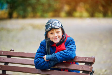 梦想飞翔。 一个孩子穿着复古的空气头盔和防护眼镜在公园里玩耍。