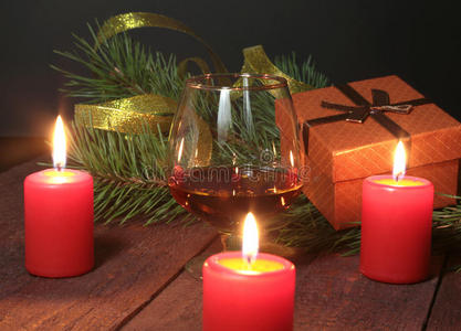 圣诞构图与玻璃干邑，礼品盒和蜡烛在木制桌子上